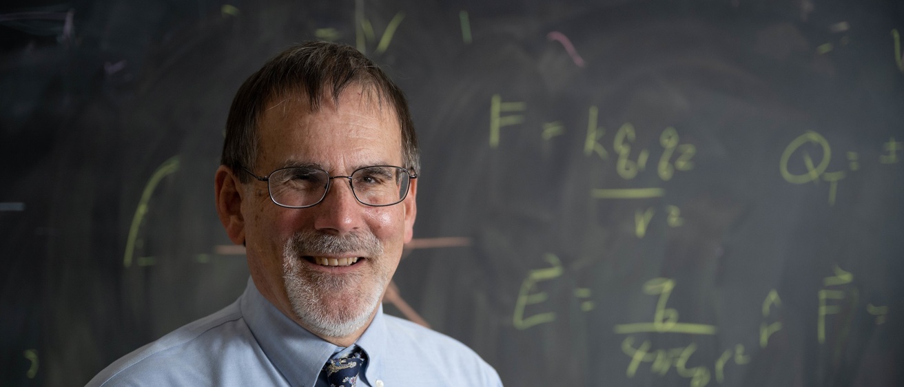 Craig Kletzing in front of a blackboard equations